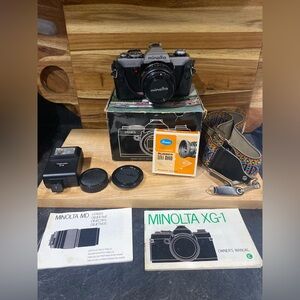 Vintage Minolta XG-1 camera with several accessories, papers and box